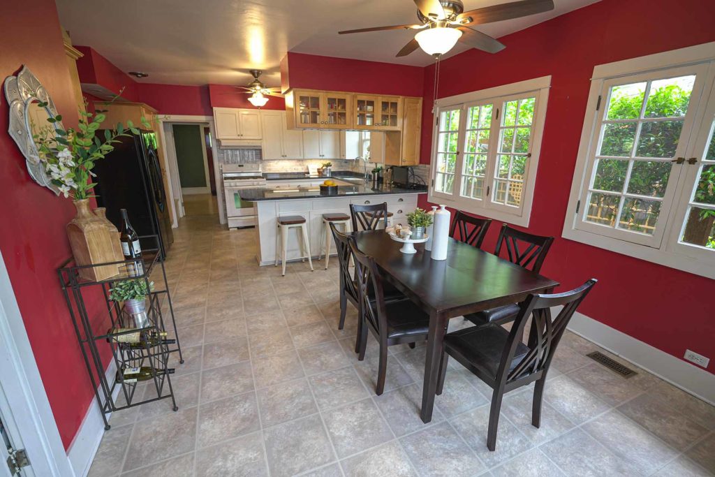 Dining room and kitchen of century-old house with red walls and brown tile floors